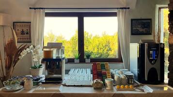 Un'area colazione a buffet con macchina del caffè, angolo tè e diversi cibi.