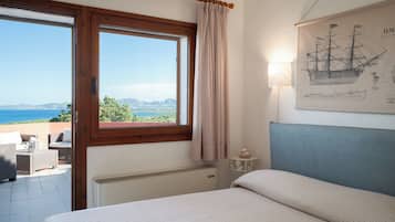 A bedroom with a bed, a window with curtains, a radiator, a wall-mounted lamp, and a framed map.