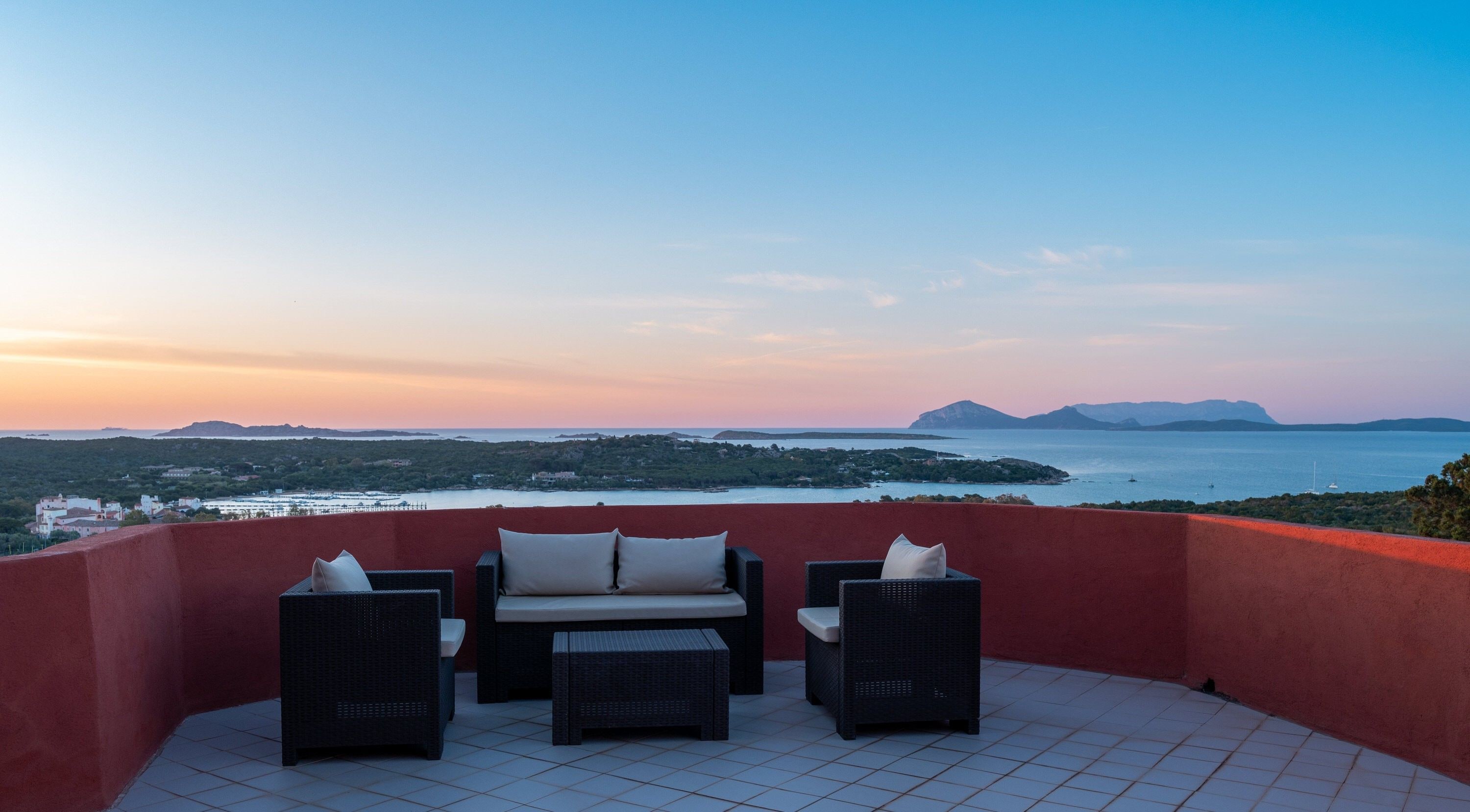 A terrace with wicker furniture and a view of the sea.