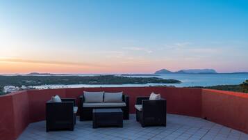 A terrace with wicker furniture and a view of the sea.