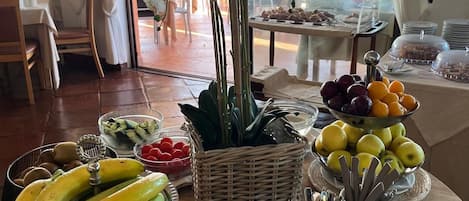 Een ontbijtbuffet met fruit, een rieten mand en een tafel met borden en bestek.