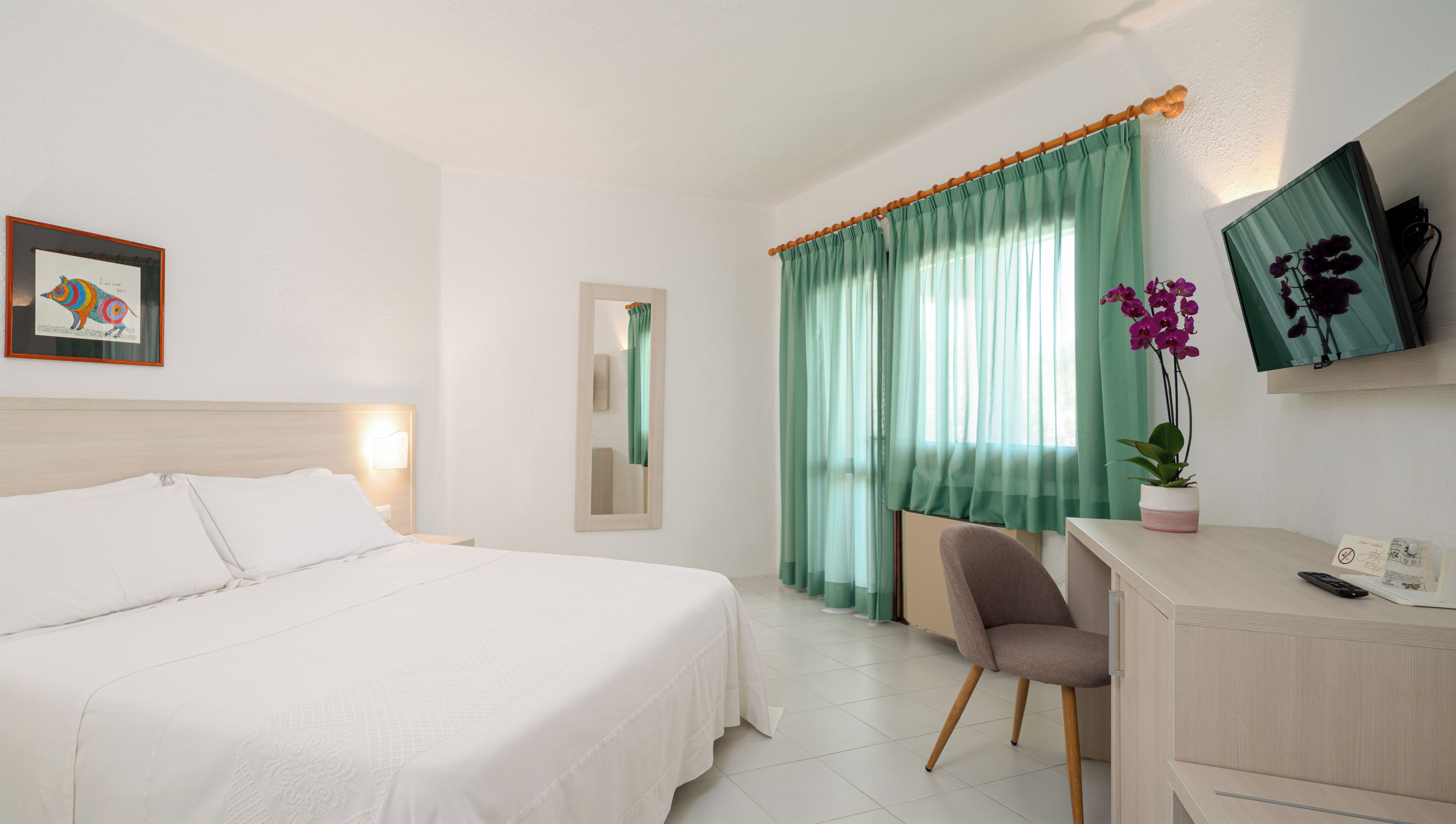 Une chambre d’hôtel équipée d’un lit, d’un bureau, d’une chaise, d’une télévision et d’une fenêtre avec des rideaux.
