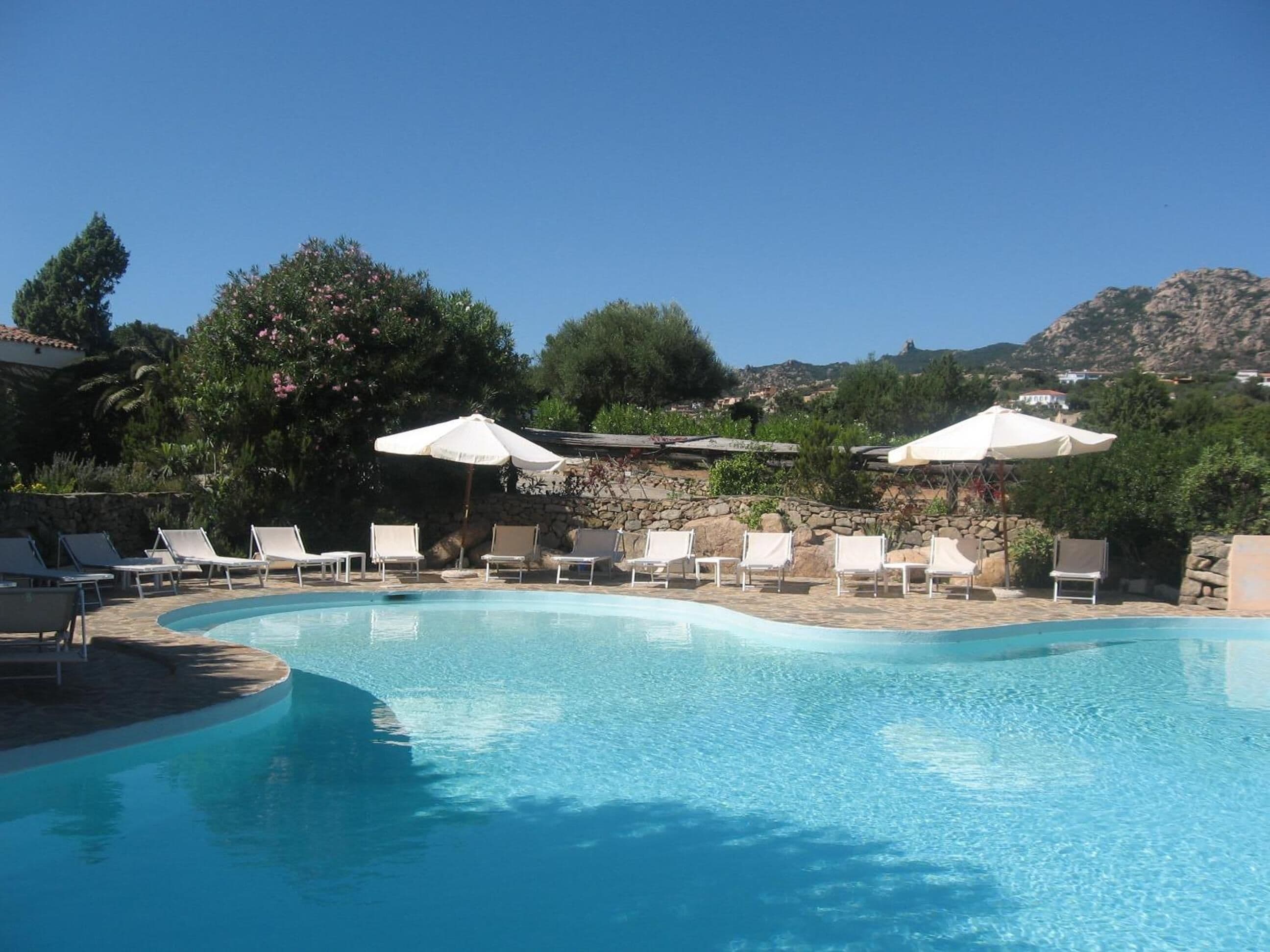 Een buitenzwembad, parasols bij het zwembad en ligstoelen