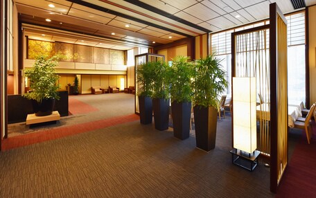 A spacious lobby with a high ceiling, multiple seating areas, and large potted plants.