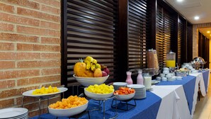 A buffet setup with various fruits and dishes on a table, surrounded by brick walls and wooden slats. - Hotel Madisson Inn Luxury By Geh Suites (Bogotá)