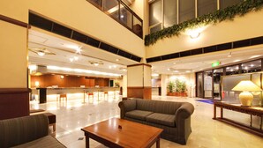 Um hall amplo com balcão de recepção, área de estar e uma grande janela.