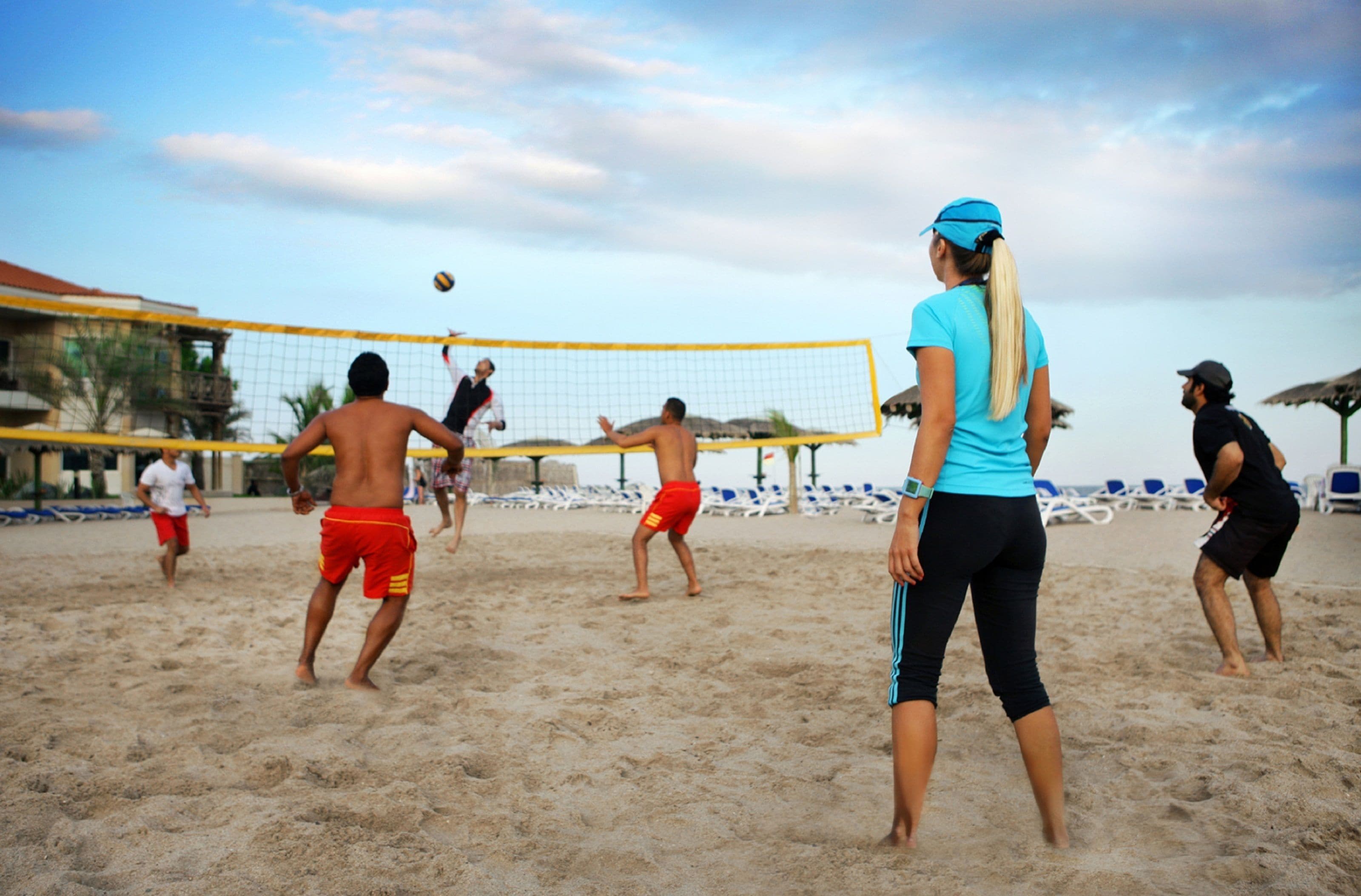 Jogo de voleibol de praia com jogadores trajando diferentes roupas.