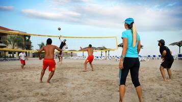 Jogo de voleibol de praia com jogadores trajando diferentes roupas.