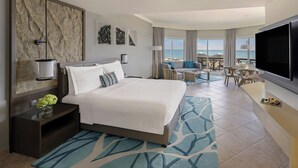A hotel room with a large bed, a TV, a balcony with a view of the sea, and a dining area. - Fujairah Rotana Resort & Spa (Al Aqah)