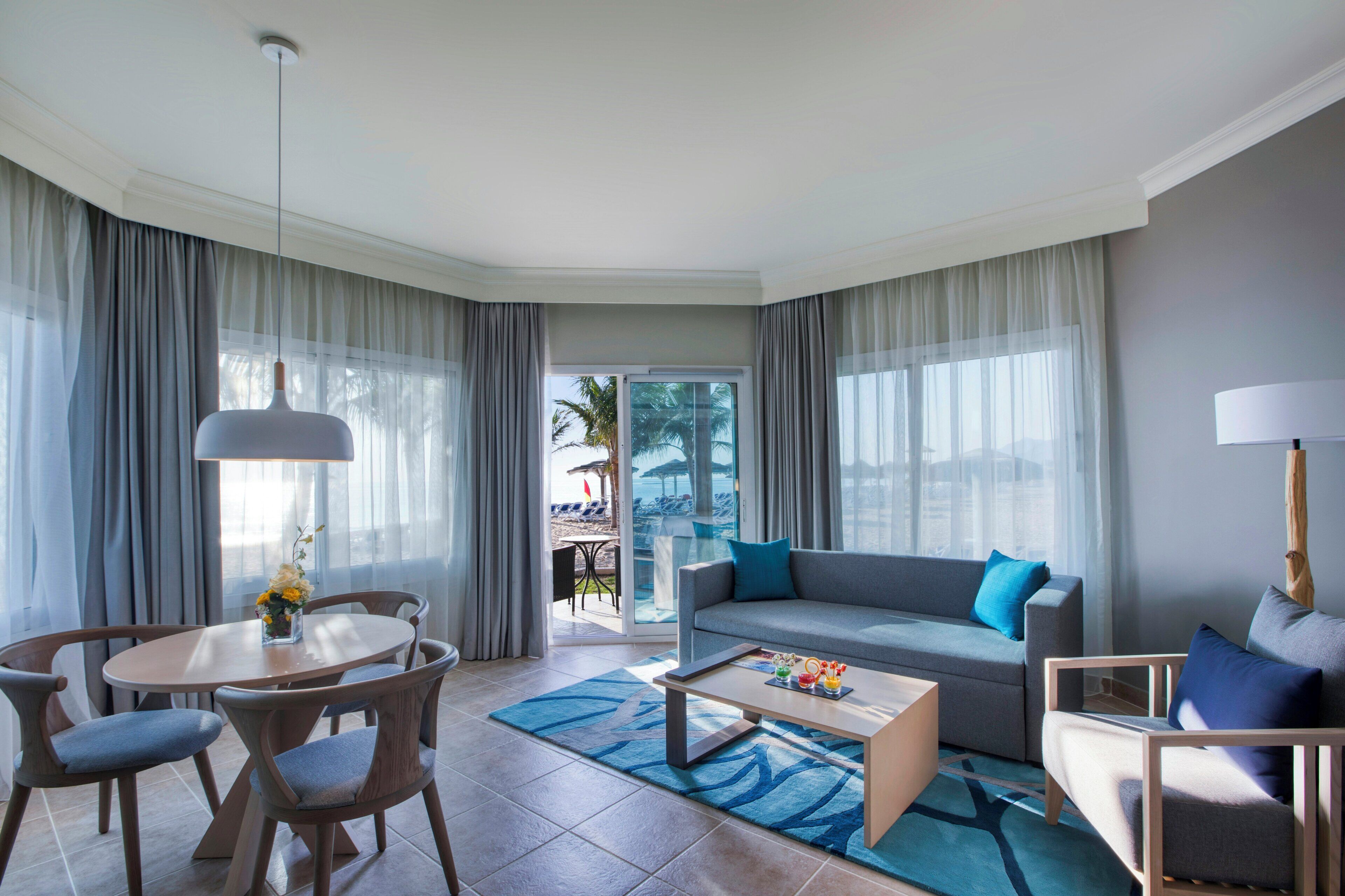 A modern living room with a sofa, coffee table, chairs, and a view of the outdoors.