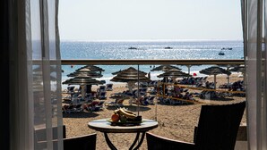 A beach view from a room with a table and chairs, beach umbrellas, and lounge chairs. - Fujairah Rotana Resort & Spa (Al Aqah)