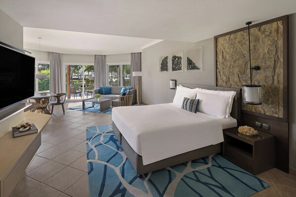 Habitación de hotel con una cama grande, escritorio, televisor y vistas al exterior.