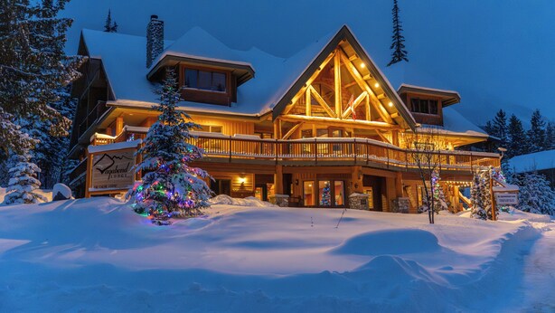 Eine Lodge mit einer markanten Holzfassade, einem Balkon und einer verschneiten Landschaft.