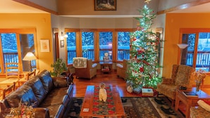 Ein gemütliches Wohnzimmer mit Kamin, Weihnachtsbaum und Blick auf eine Terrasse.