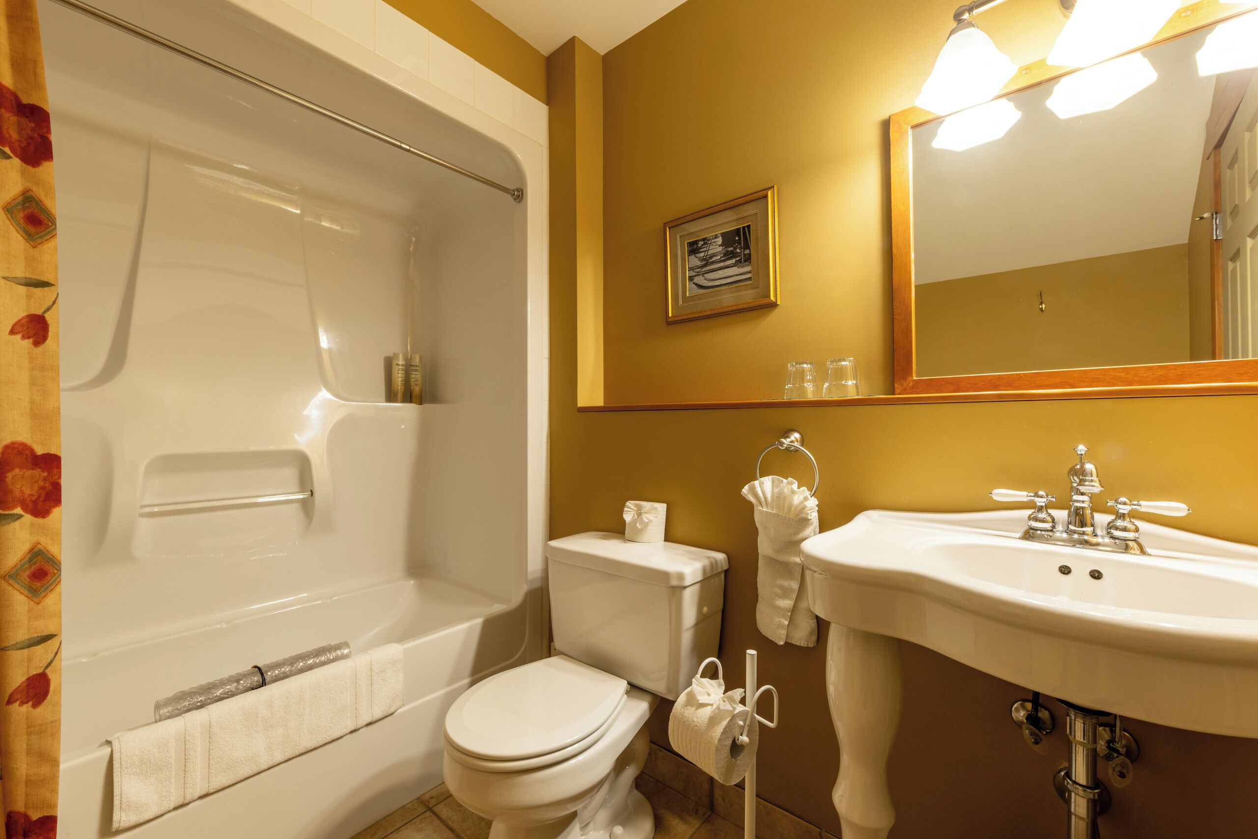 A bathroom with a bathtub, toilet, sink, and a framed picture on the wall.