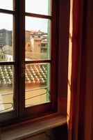 Una finestra con vista sul tetto di un edificio e una tenda parzialmente scostata.