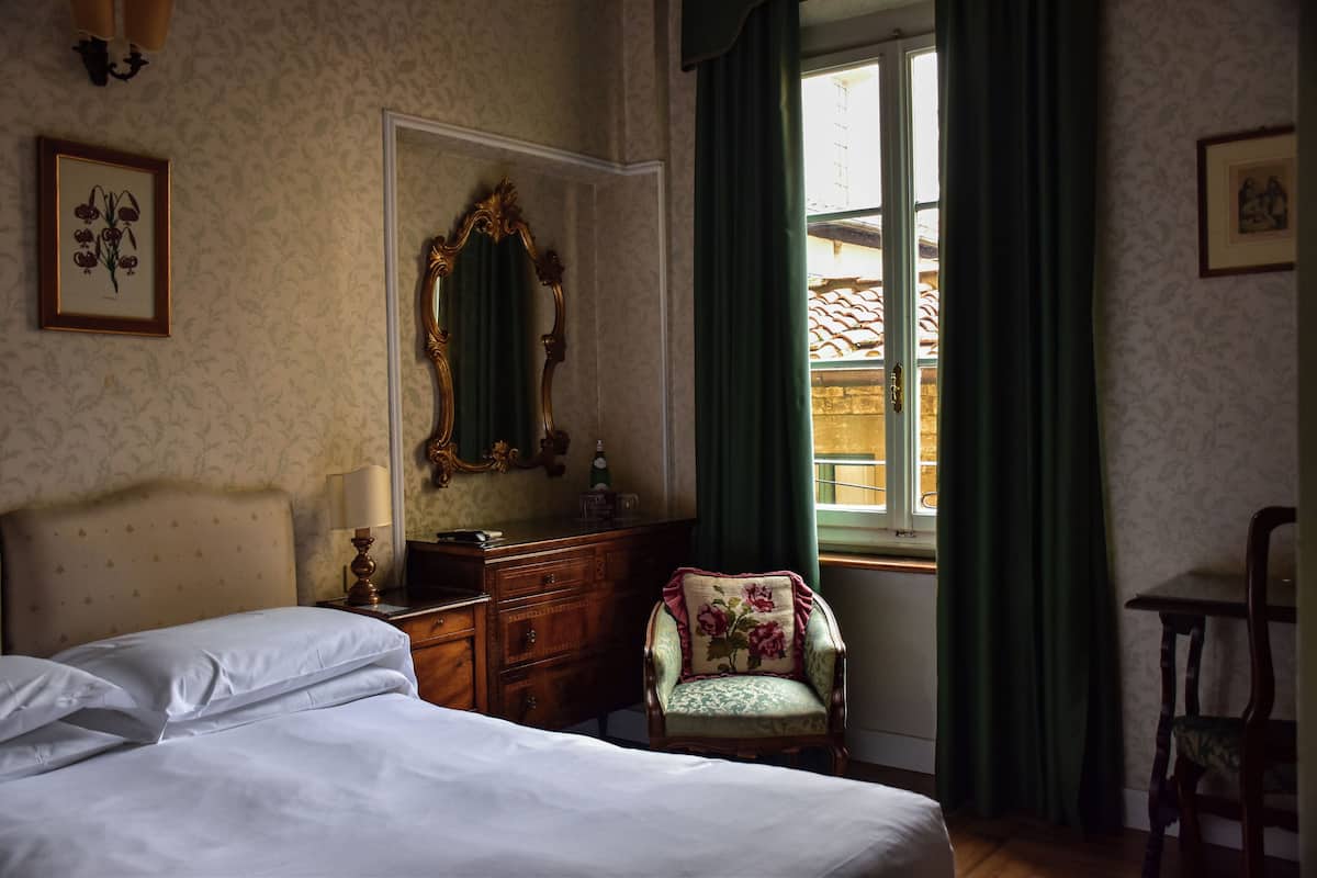 A bedroom with a bed, dresser, chair, and a large mirror.
