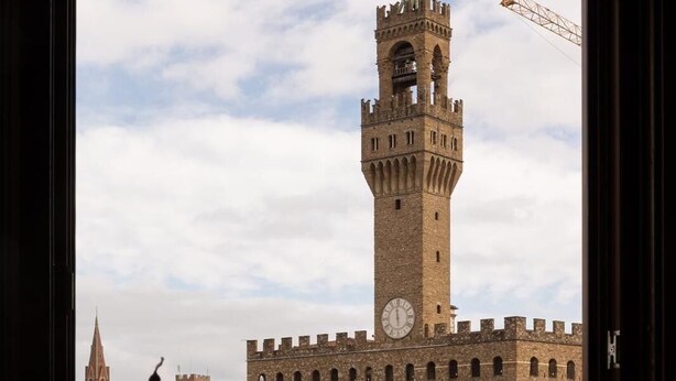 A table with wine glasses and cutlery, overlooking a historic building with a prominent tower. - Hotel Hermitage (Florence)