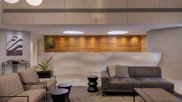 A modern lobby with a reception desk, sofas, and a coffee table.