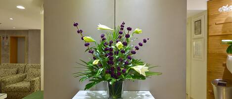 A reception area with a glass-top table holding a vase of flowers.
