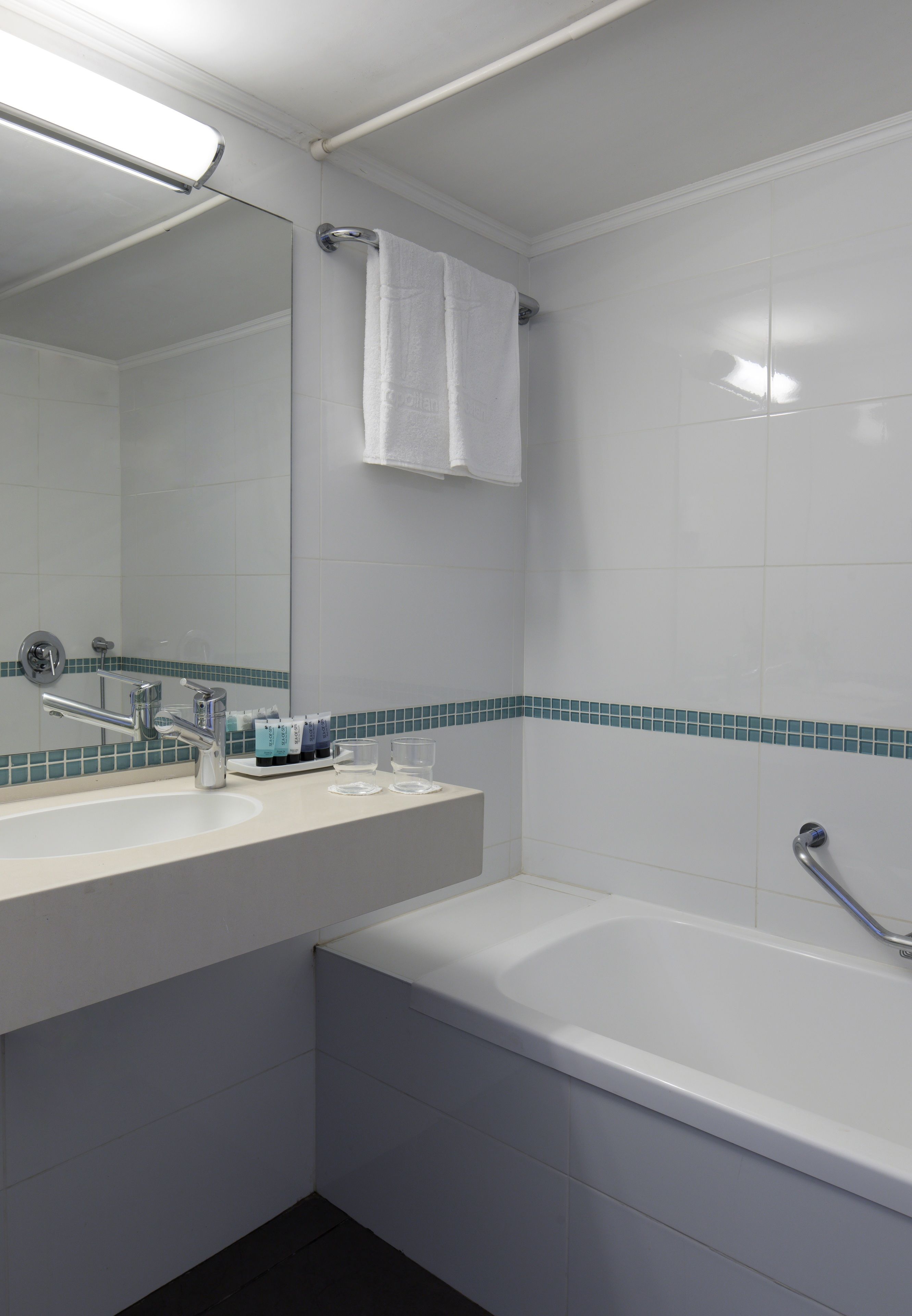 A bathroom with a white sink, mirror, and bathtub.