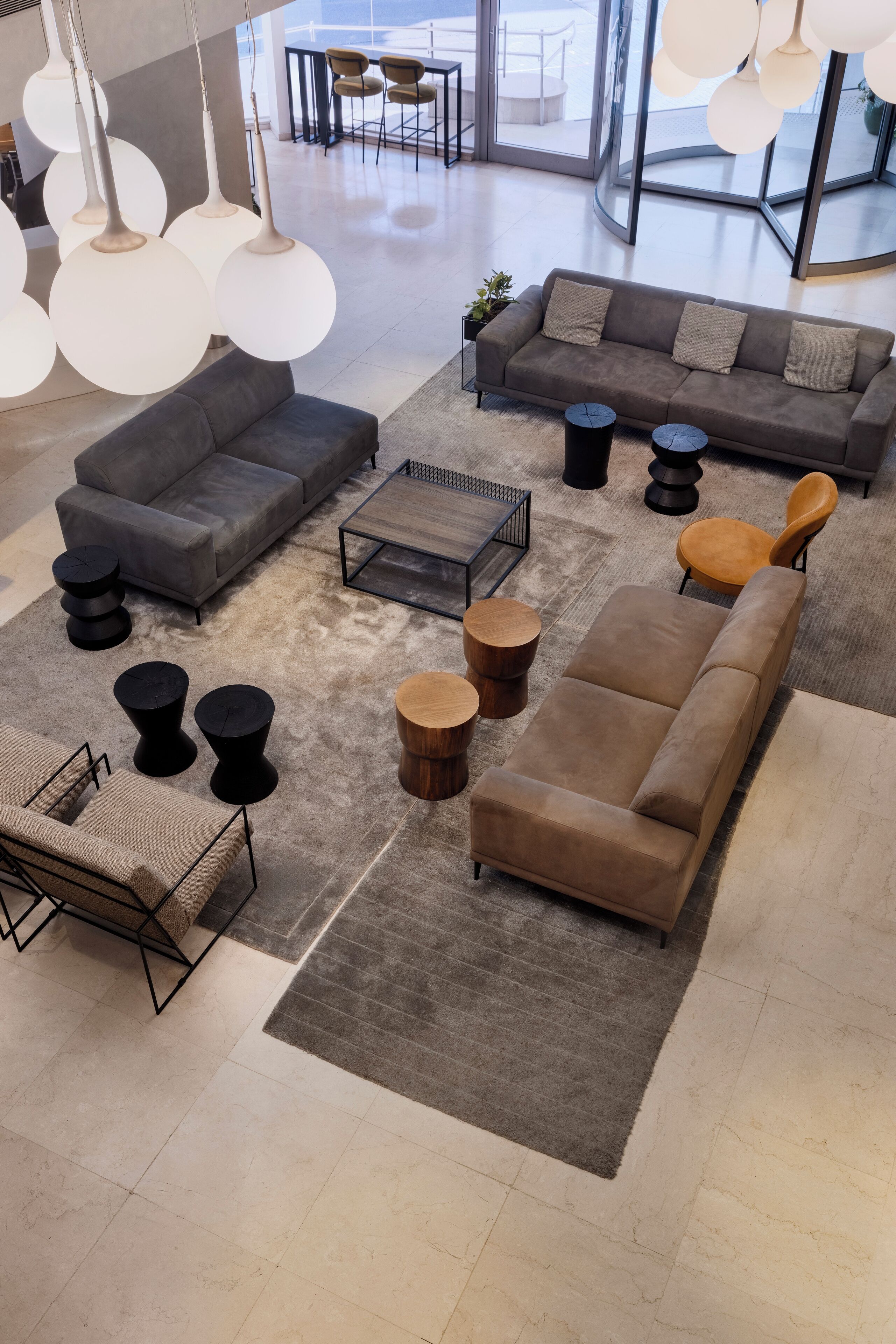 A modern interior with a grey sofa, a brown sofa, and a coffee table. There are also black and wooden side tables.