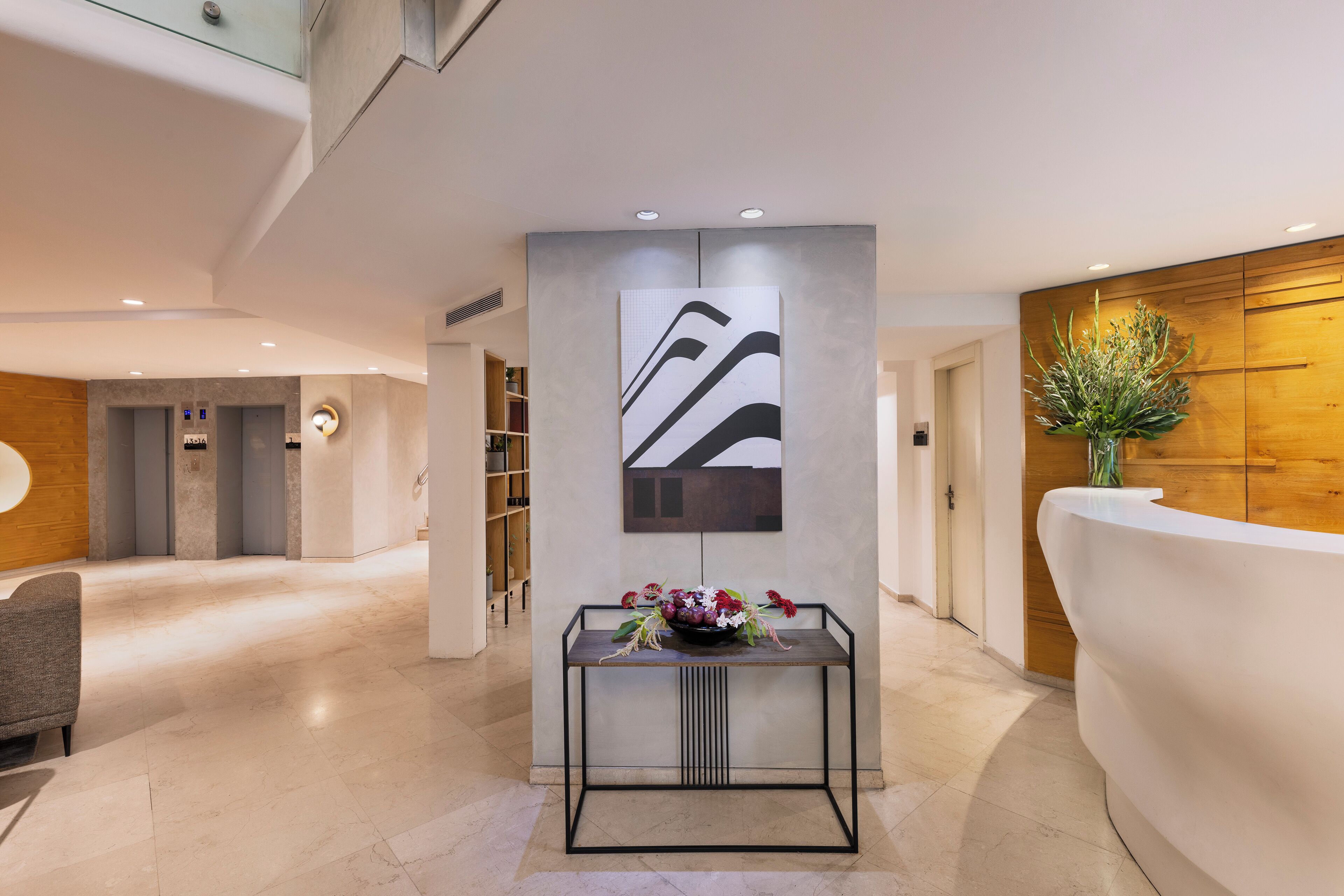 Una zona de recepción moderna con un mostrador de recepción, una obra de arte en la pared y un jarrón con flores.