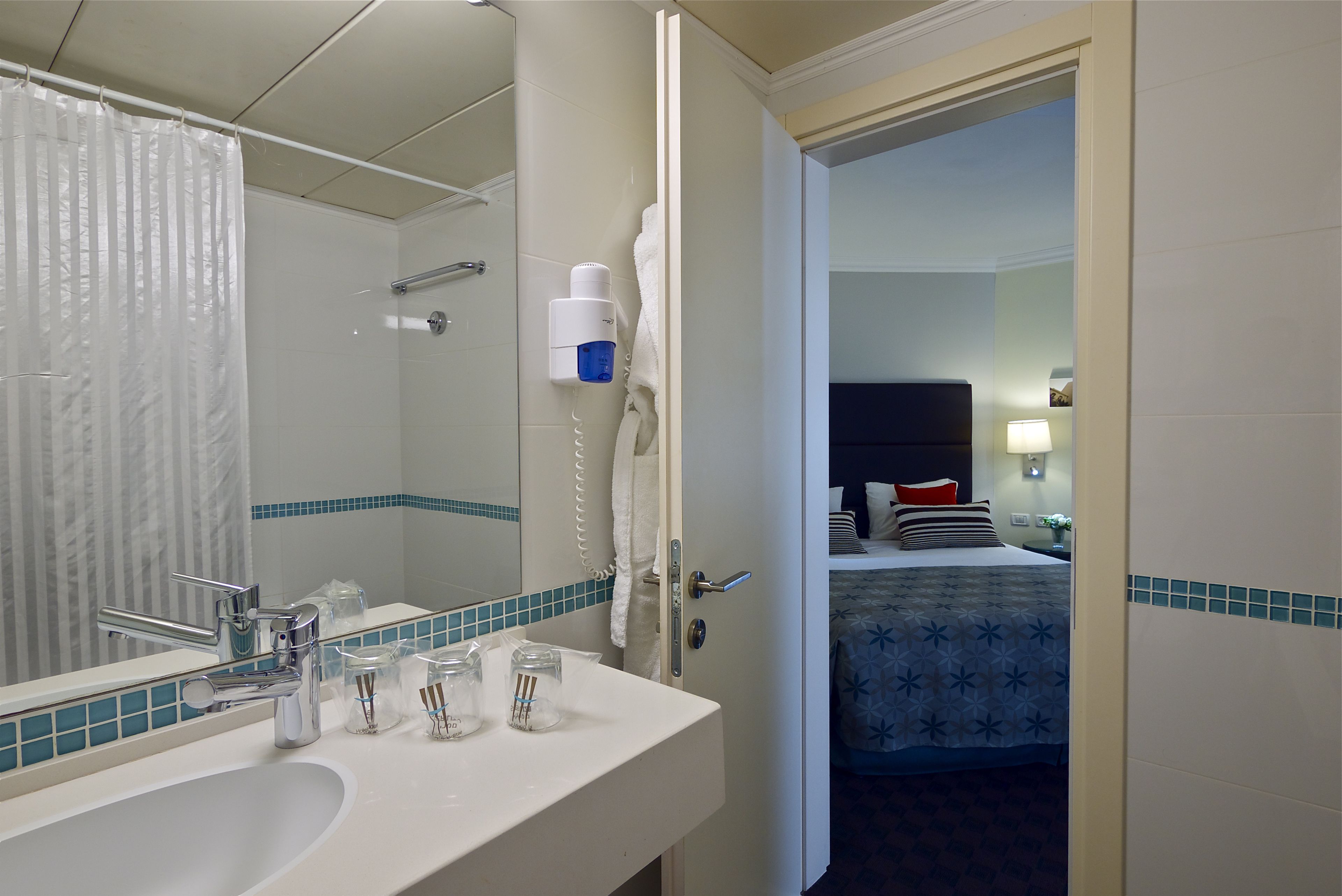 Une salle de bain d’hôtel avec un lavabo, un miroir et une douche.
