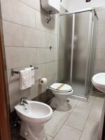 Un baño moderno con dos inodoros, un lavamanos, una ducha y un dispensador de papel higiénico.