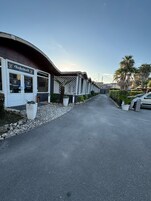 Un hotel con facciata curva, area salotto esterna e un vialetto lastricato.