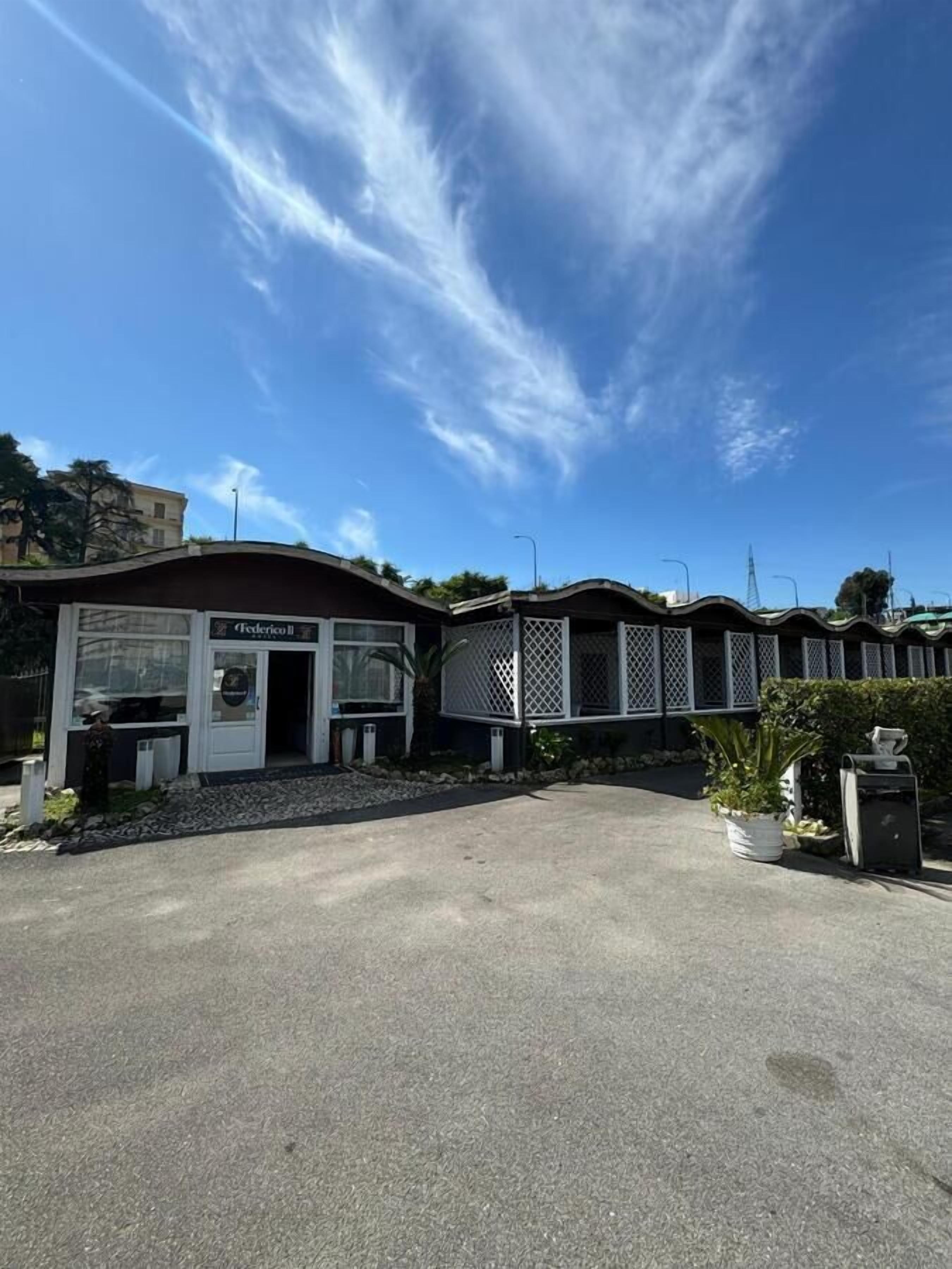 A row of single-story buildings with a flat roof, a covered outdoor area, and a clear sky.