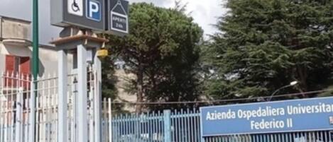 Placa de hotel com ícones de comodidades, placa de estacionamento e placa com o nome de uma universidade.