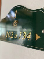 Egy fekete tábla arany színű felirattal, amely a 102-es és a 134-es szobaszámokat jelöli.