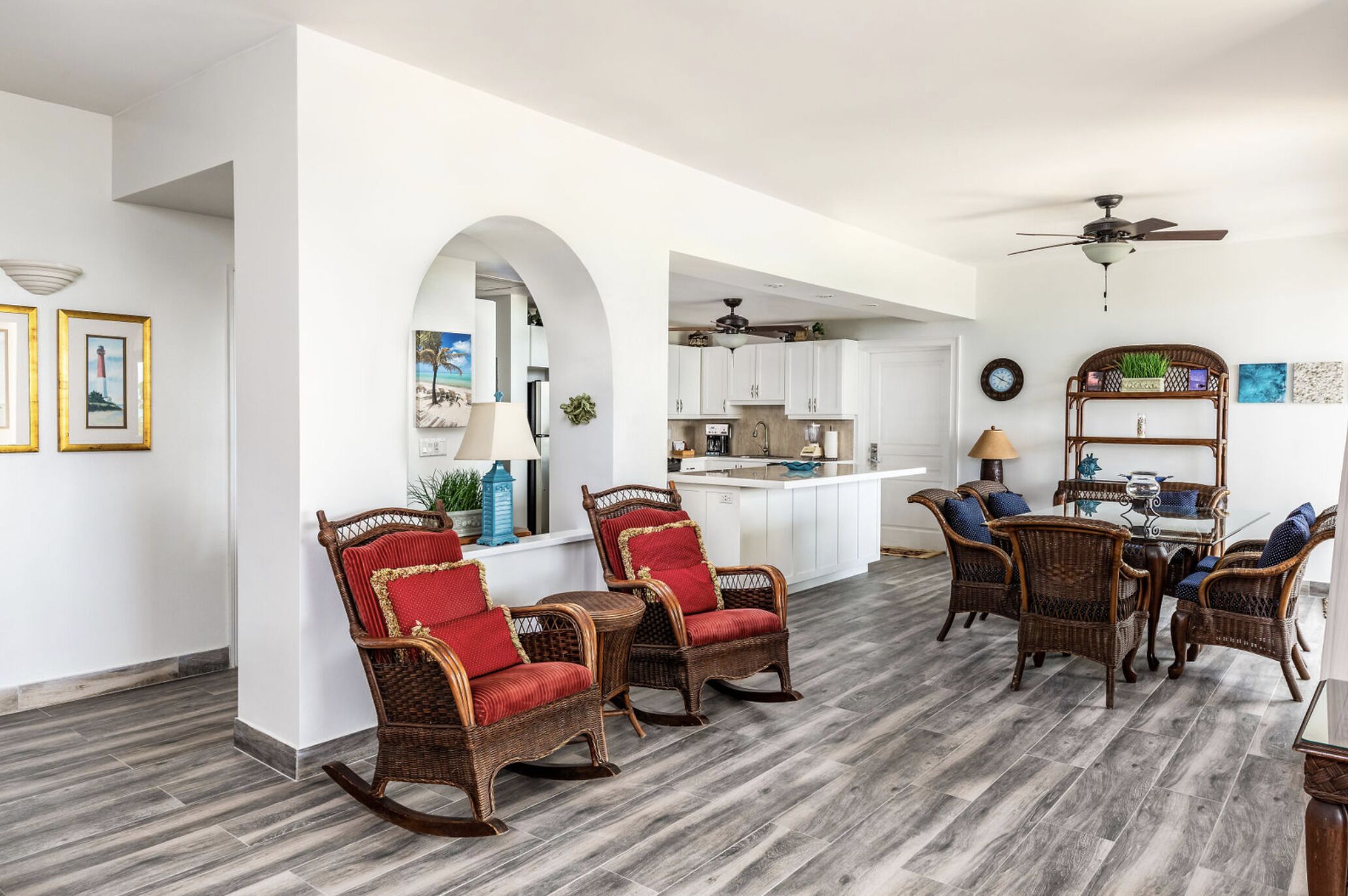 A spacious living area with wicker furniture, a dining table, and a kitchen in the background.
