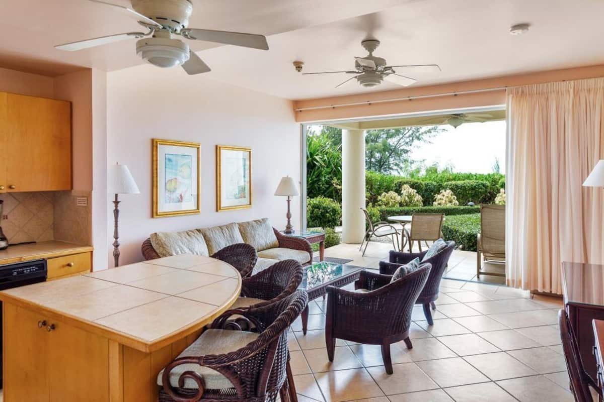 A spacious room with a dining area, a sofa, and a view of a garden.