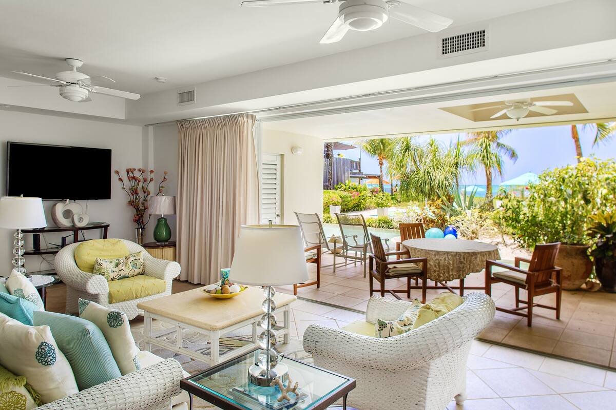 A spacious living room with a flat-screen TV, comfortable seating, and a patio area with outdoor furniture.
