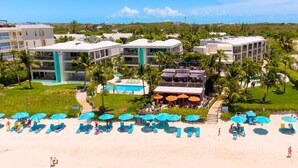 A resort with multiple buildings, a pool area, and beachside lounge chairs. - Coral Gardens on Grace Bay (Providenciales)