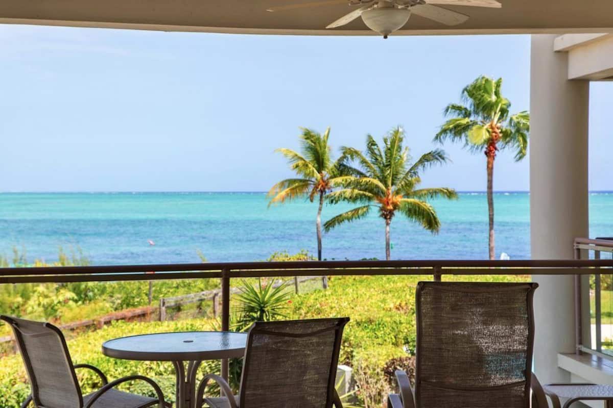 A balcony with a view of the ocean and palm trees.