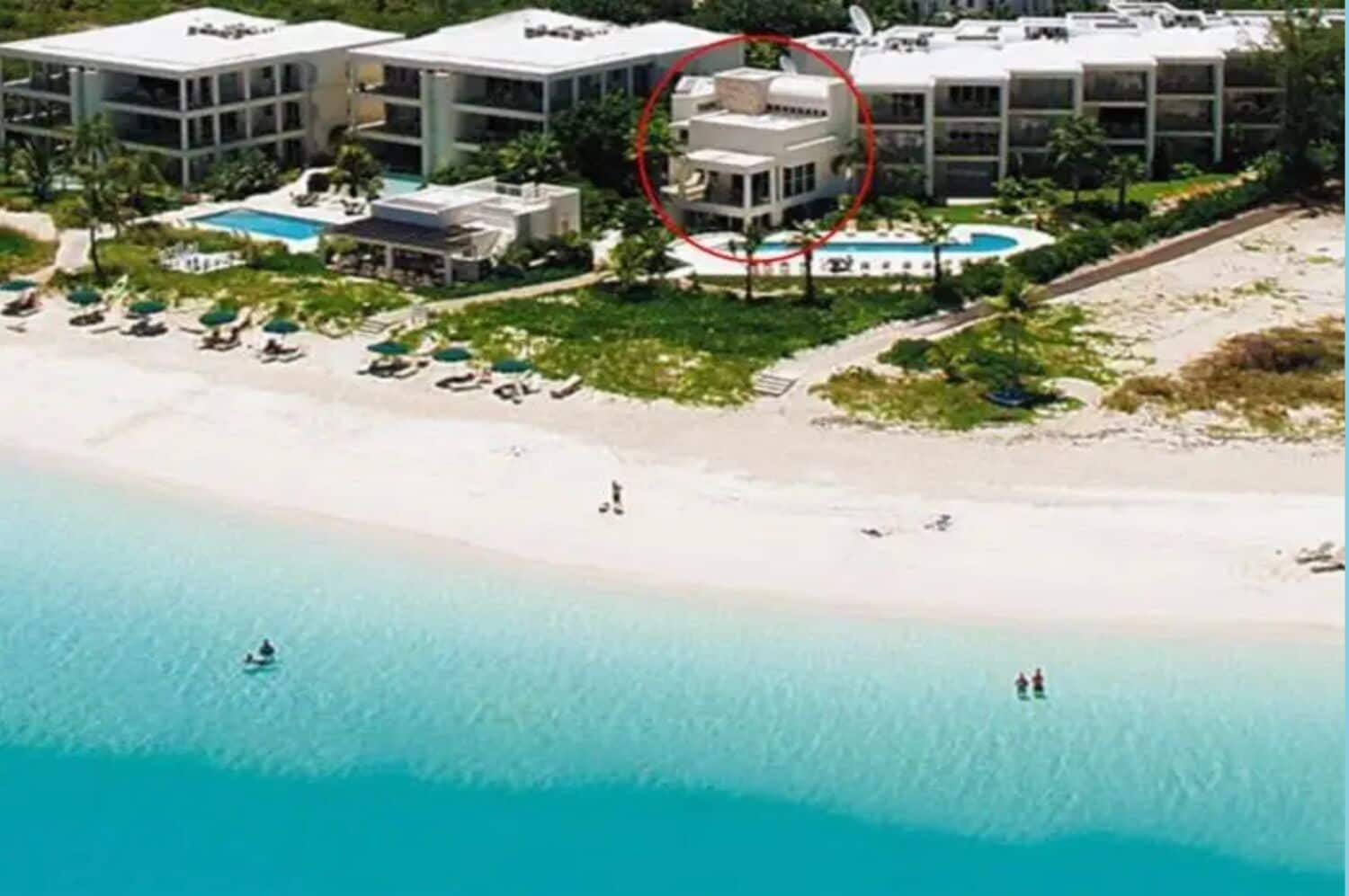 An aerial view of a resort with multiple buildings, a beach, and a pool area.