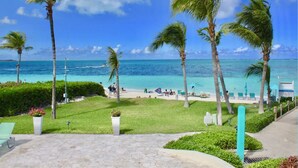 A beach view with palm trees, a clear sky, and a calm sea. - Coral Gardens on Grace Bay (Providenciales)