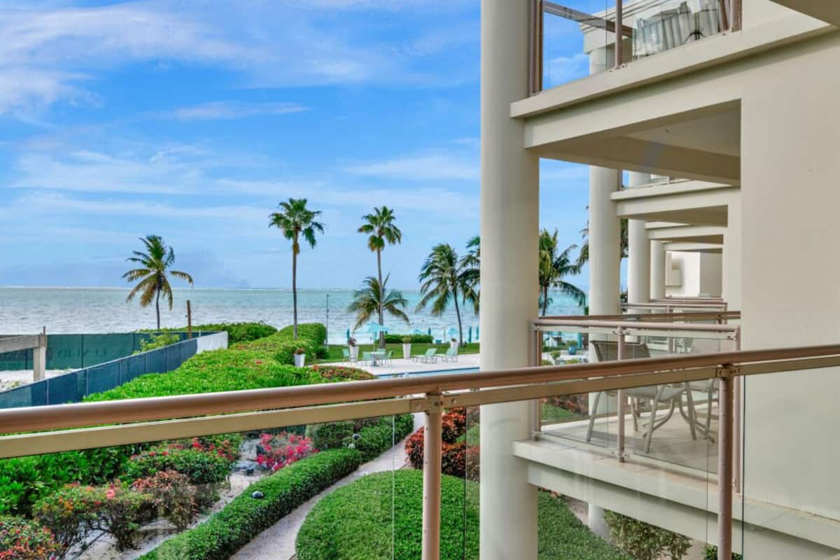 A hotel balcony with a view of the ocean and palm trees.