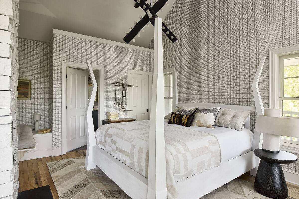 Une chambre à coucher avec un lit à baldaquin, une porte blanche et une fenêtre donnant sur un beau paysage.