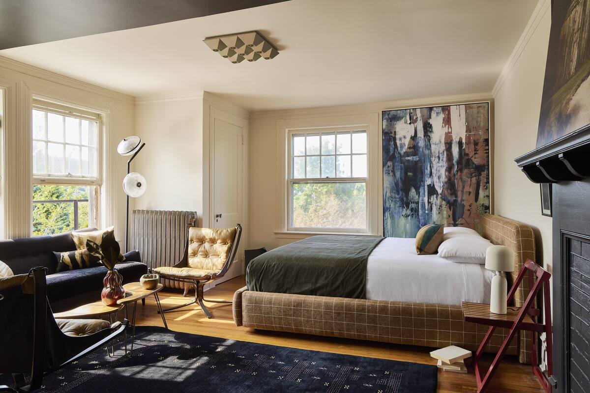 Une chambre à coucher avec un grand lit, un canapé, un fauteuil et une cheminée.