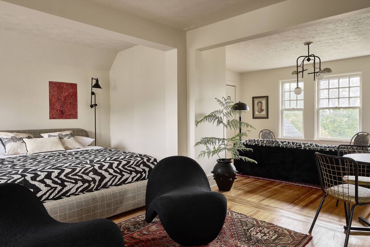 Une pièce spacieuse avec un grand lit, un coin repas et une vue sur l’extérieur.