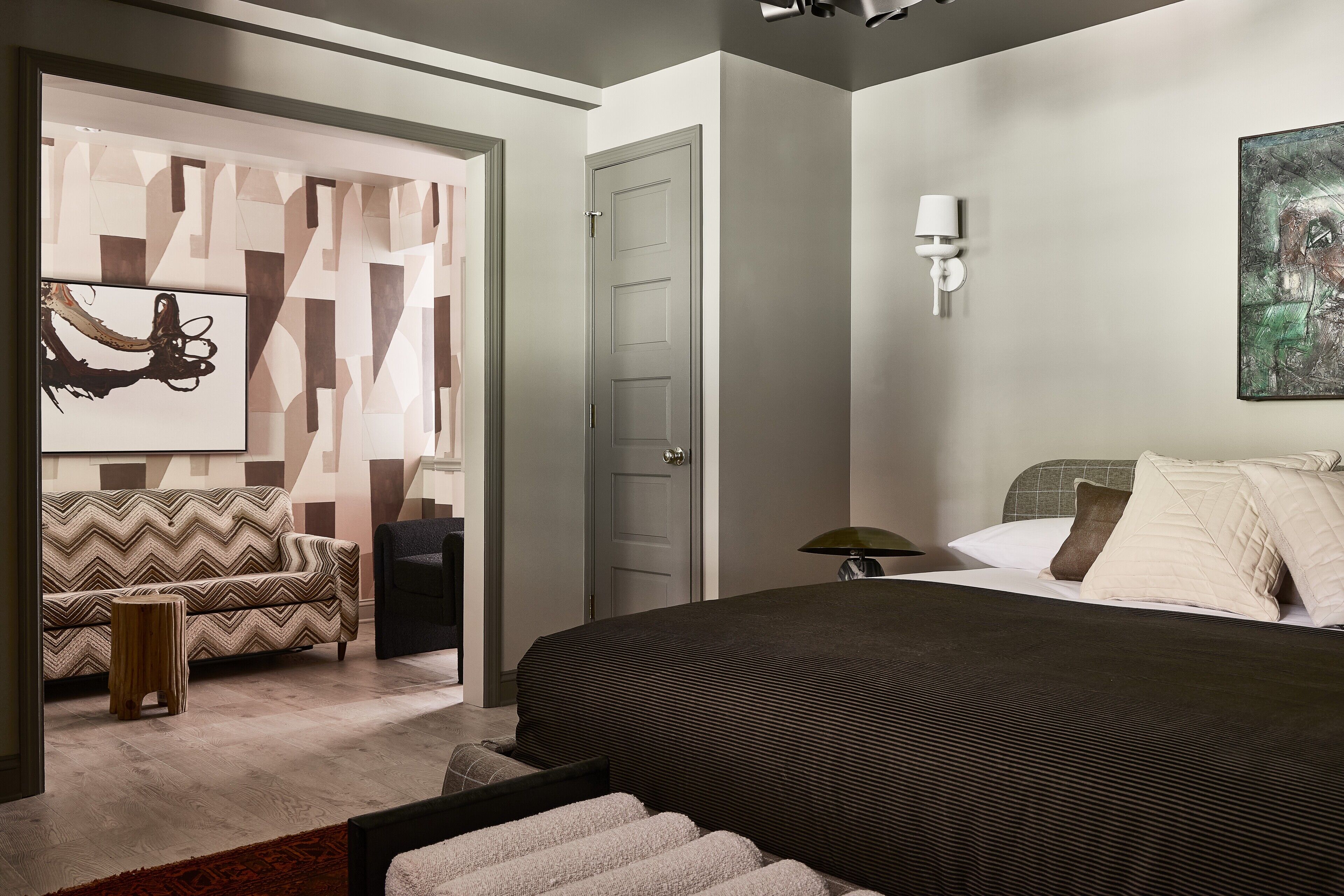 Una camera da letto moderna con un letto grande, una poltrona e una parete decorativa.