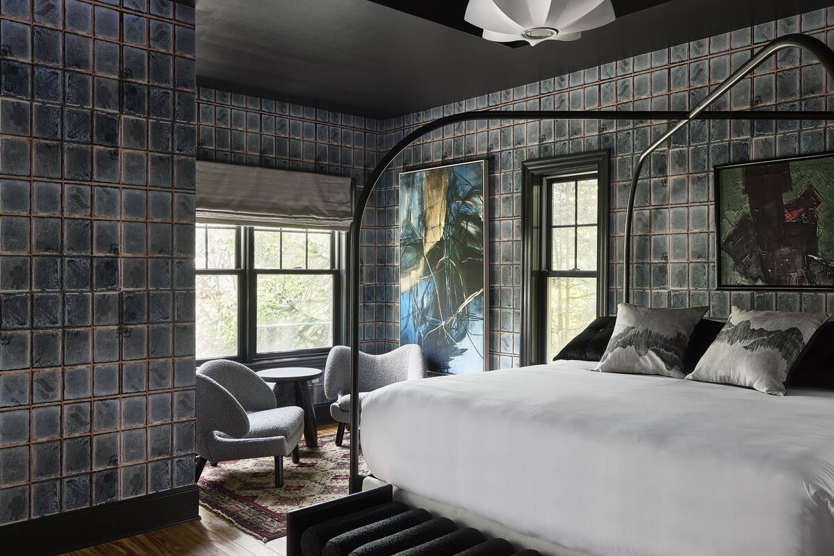 Une chambre à coucher moderne avec un grand lit, une chaise, une petite table et une fenêtre.