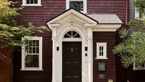A dark red building with a black front door, white trim, and a small window to the left. - Blind Tiger Asheville (Asheville)