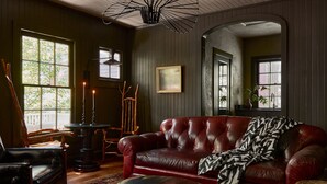 A cozy living room with a red leather sofa, a wooden coffee table, and a patterned rug. - Blind Tiger Asheville (Asheville)
