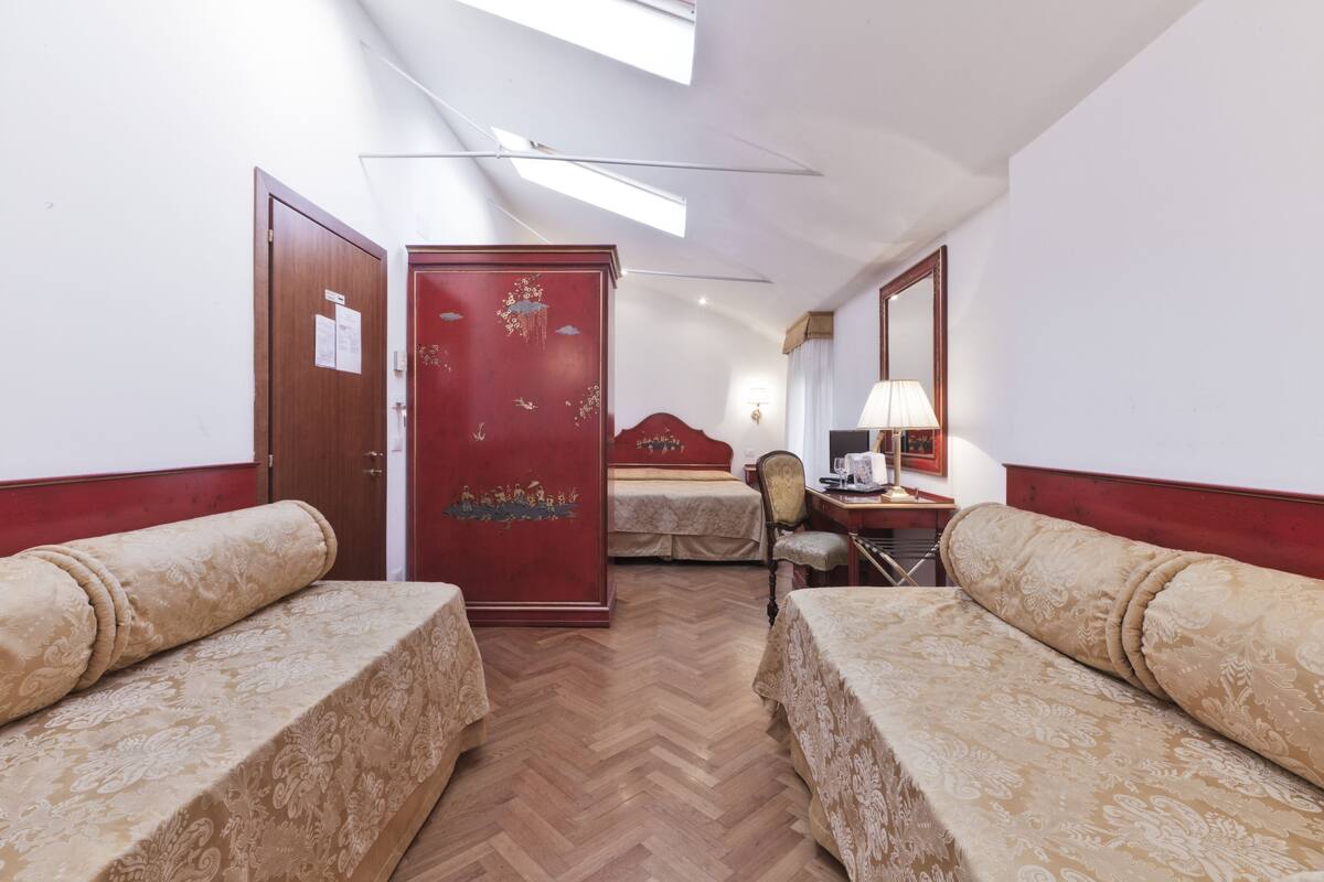 Een hotelkamer met twee bedden, een bureau, een stoel en een kledingkast.