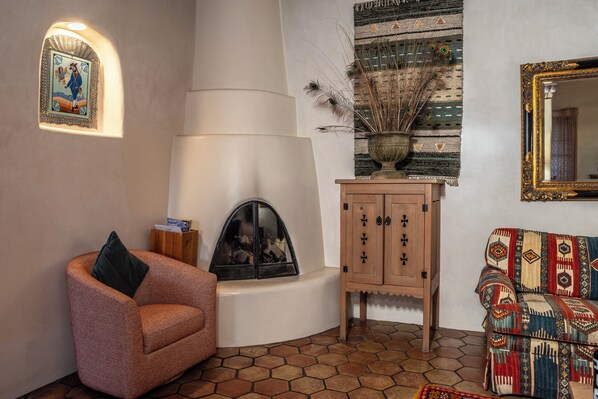 A cozy living room with a fireplace, a patterned sofa, and a decorative mirror.